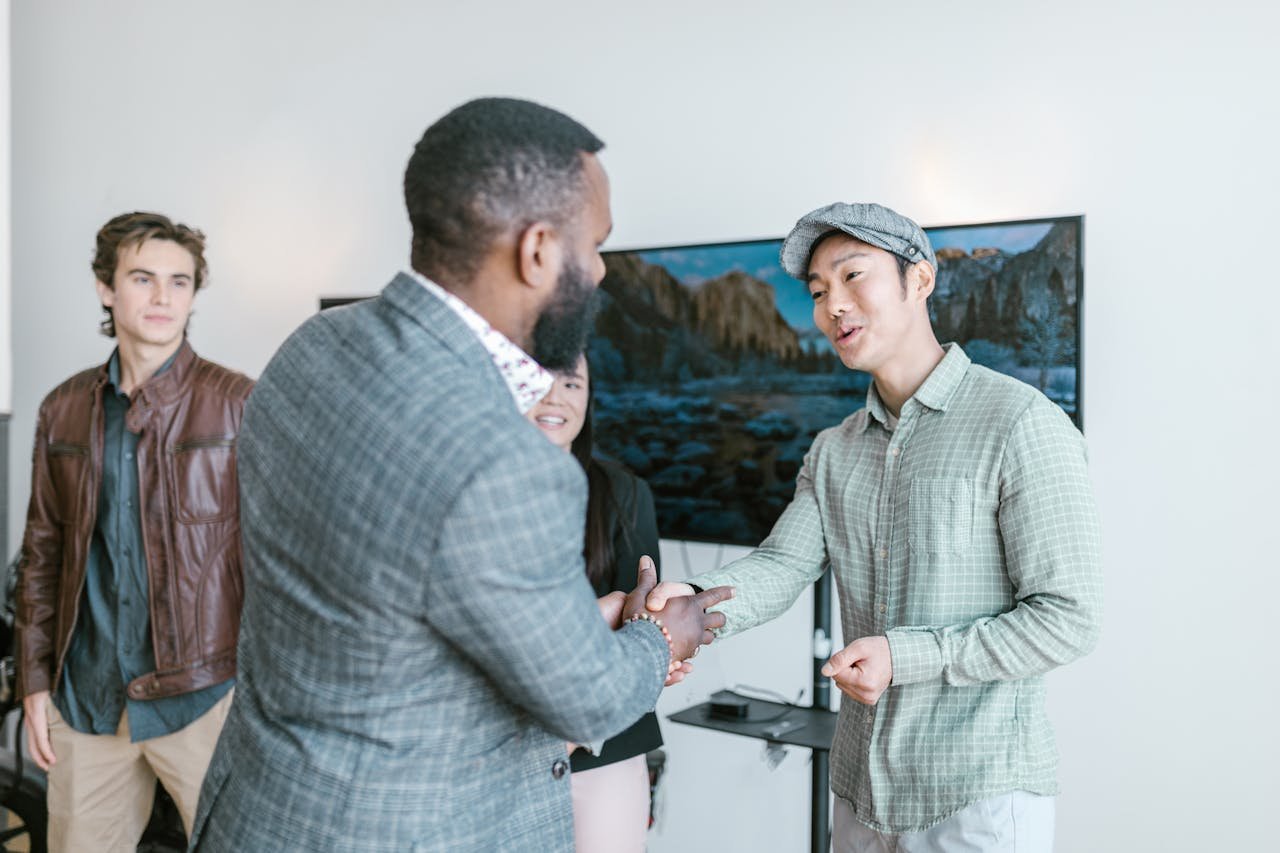 Diverse entrepreneurs engaging in a friendly handshake inside a modern office space.